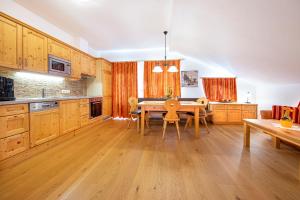 a kitchen with wooden cabinets and a table with chairs at Ferienwohnungen Behamhof in Neukirchen am Großvenediger