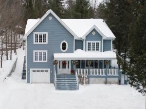 une maison bleue avec une terrasse couverte dans la neige dans l'établissement Au coeur de Saint-Sauveur, à Saint-Sauveur-des-Monts
