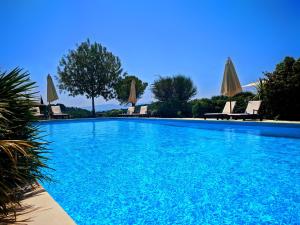 una gran piscina con sillas y sombrillas en Domaine de Palats en Laure-Minervois