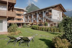 a hotel with two chairs and a table in the grass at Hotel Alpenblick in Lutago