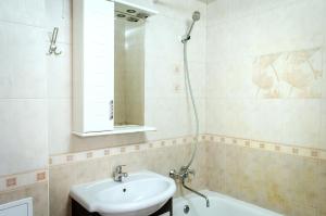 een badkamer met een wastafel, een spiegel en een bad bij Pobedy avenue in Charkov
