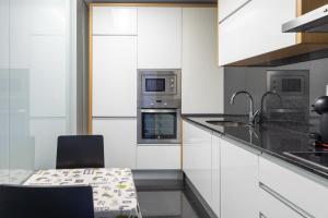 a kitchen with white cabinets and a black counter top at Porto Dragão in Porto