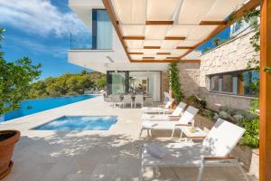 a patio with white chairs and a swimming pool at Villa Anabel in Hvar
