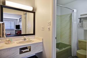 une salle de bain avec un lavabo, un miroir et une douche dans l'établissement Expedition Lodge Moab Arches National Park, à Moab