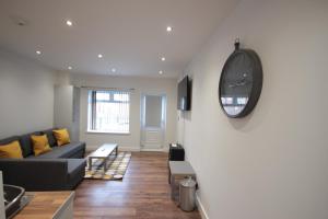 a living room with a couch and a clock on a wall at Studio 332 in Hull