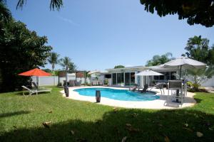 einen Pool mit Stühlen und Sonnenschirmen im Hof in der Unterkunft Heated pool ,3 bedroom bungalow ,minutes from the beach in Deerfield Beach