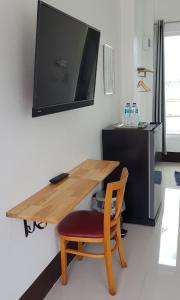 einem Holztisch mit einem Stuhl und einem TV an der Wand in der Unterkunft บ้านเชียงรายรีสอร์ท Baan Chiangrai Resort in Chiang Rai