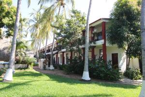 une rangée de palmiers devant un bâtiment dans l'établissement Hotel Albatros, à Puerto Escondido