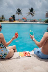 duas pessoas sentadas ao lado de uma piscina com comida e bebidas em Grand Caribe Belize em San Pedro