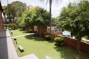 a yard with benches and trees next to a building at Grande Hotel Atibaia in Atibaia