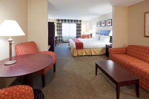 a hotel room with a bed and a table and chairs at Holiday Inn Express Hotel & Suites Freeport by IHG in Freeport +50 photos