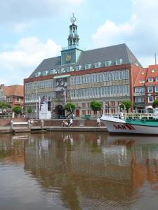 um barco está ancorado em frente a um grande edifício em Piacere Emden em Emden