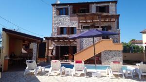 a group of chairs and an umbrella next to a pool at Casa Bozzero in Krnica
