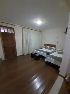two beds in a room with wooden floors and a door at Casa centro histórico in Diamantina