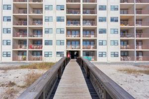 a building on the beach with a wooden boardwalk at Island Shores Condos II in Gulf Shores