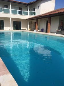 una grande piscina blu di fronte a una casa di Itanhaém Maravilhosa, Bilhar, Sky, WiFi, Piscina e churrasqueira grande, Gramado, Casa linda de alto padrão a 600m praia a Itanhaém