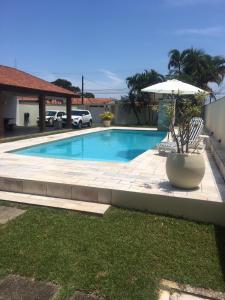 una piscina con tavolo e ombrellone di Itanhaém Maravilhosa, Bilhar, Sky, WiFi, Piscina e churrasqueira grande, Gramado, Casa linda de alto padrão a 600m praia a Itanhaém