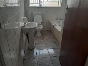 a bathroom with a toilet and a sink and a tub at New Lodge in Bloemfontein