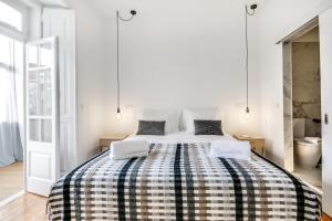 a white bedroom with a bed with a checkered blanket at Saldanha Pool & Garden in Lisbon