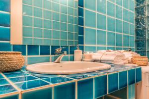 a blue tiled bathroom with a sink and towels at Design Apartments Sassari-Torre Tonda in Sassari