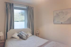 ein Schlafzimmer mit einem Bett und einem Fenster in der Unterkunft Tigh Na Mara Holiday Home in Aultbea