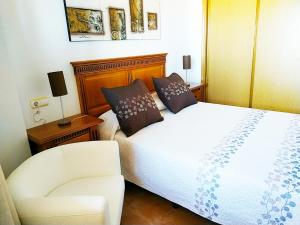 1 dormitorio con 1 cama blanca y 1 silla en Marina Vistamar, en Mojácar