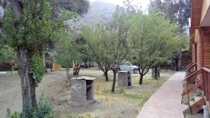 une cour avec des arbres et une voiture en arrière-plan dans l'établissement Cabañas y Hotel Rural Mirador del Maipo, à San José de Maipo
