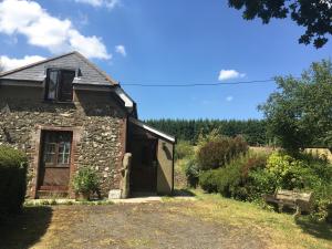 an old stone building with a door in a yard at Meadow Sweet Cottage in Okehampton