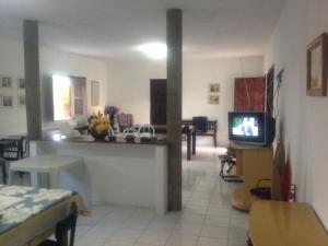a living room with a television and a dining room at Repouso do Mar Residence in Aracati