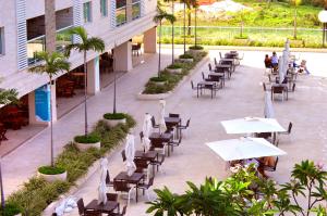 an outdoor patio with tables and chairs and palm trees at Salinas Park Resort in Salinópolis