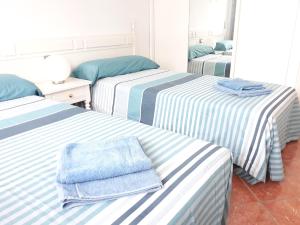 3 Betten in einem Zimmer mit blauen und weißen Streifen in der Unterkunft Yumbo - Apartment in Playa del Ingles