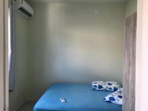 Habitación pequeña con cama con sábanas y almohadas azules. en Casa temporada Mariscal, Bombinhas-SC, en Bombinhas