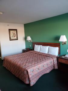 a hotel room with a bed with a red bedspread at Super 7 Inn Tecumseh in Tecumseh