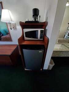 a microwave sitting on top of a wooden stand at Super 7 Inn Tecumseh in Tecumseh