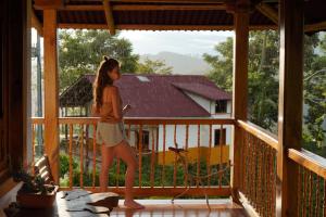 a young girl standing on a porch looking out the window at Finca TRADICIONAL EL OTOÑO in Pijao