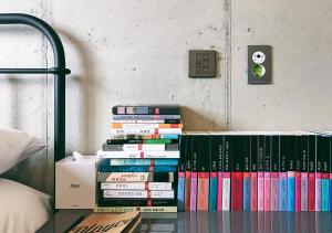 a stack of books on a shelf in a bedroom at Playce Camp Jeju in Seogwipo +60 photos