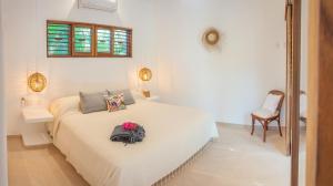 a white bedroom with a bed with flowers on it at Casa Mon Repos en Careyes in Careyes