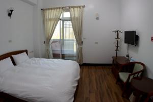 a bedroom with a bed and a window at Cuiti B&B in Fenqihu