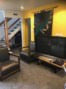 a living room with a flat screen tv and chairs at Pryor Haven Chalet Green Retreat in a Lovely Place in Christchurch