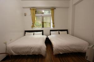 two beds in a room with a window at Cuiti B&B in Fenqihu