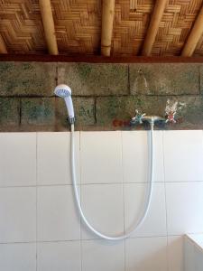 a shower with a hose attached to a wall at Bamboo Bali in Amed