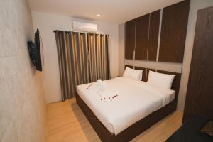 um quarto com uma cama grande e lençóis brancos em The Y Smart Hotel em Chiang Mai