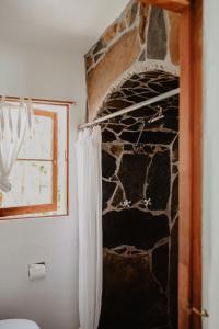 a bathroom with a stone wall and a shower curtain at Korakia Pensione in Palm Springs