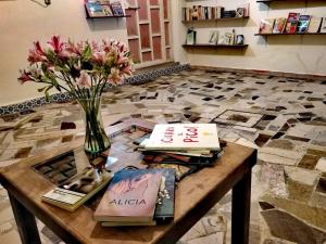 a table with books and a vase with flowers on it at Hostal Quinto Sol Huamantla in Huamantla
