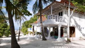 a white house on the beach with palm trees at Eco dive resort Alycastre in Maumere