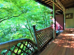 a wooden deck with a view of the trees at Ryokan Nenrinbo in Kyoto