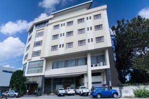 um edifício branco com carros estacionados em frente em East View Hotel em Bacolod