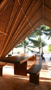 une grande table en bois assise sous un toit dans l'établissement Eco dive resort Alycastre, à Maumere