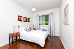 a white bedroom with a bed and a window at Camellia Cottage - PET FRIENDLY - Kwinana in Medina