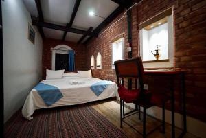 a bedroom with a bed and a desk and a brick wall at Bandipur chhen in Bandīpur